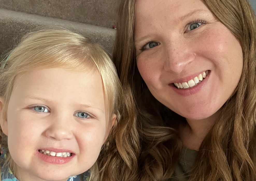 A close up head and shoulders picture of a young girl with blonde hair - and her mum who has long brown hair