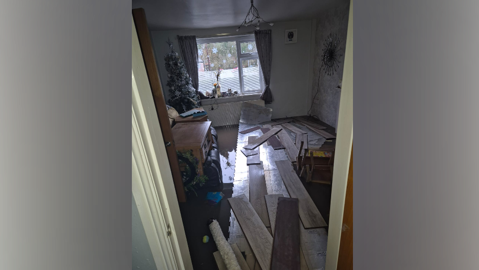 Dirty brown water and detritus lie on the floor of a living room.