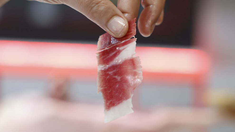 A hand holding a rolled up piece of meat.
