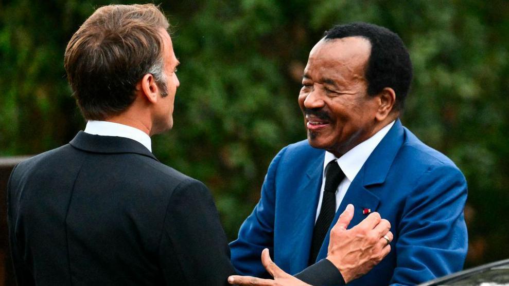 France's President Emmanuel Macron (L) welcomes Cameroon President Paul Biya during a ceremony marking the 80th anniversary of the Allied landings in Provence during World War II, at the Boulouris National Cemetery