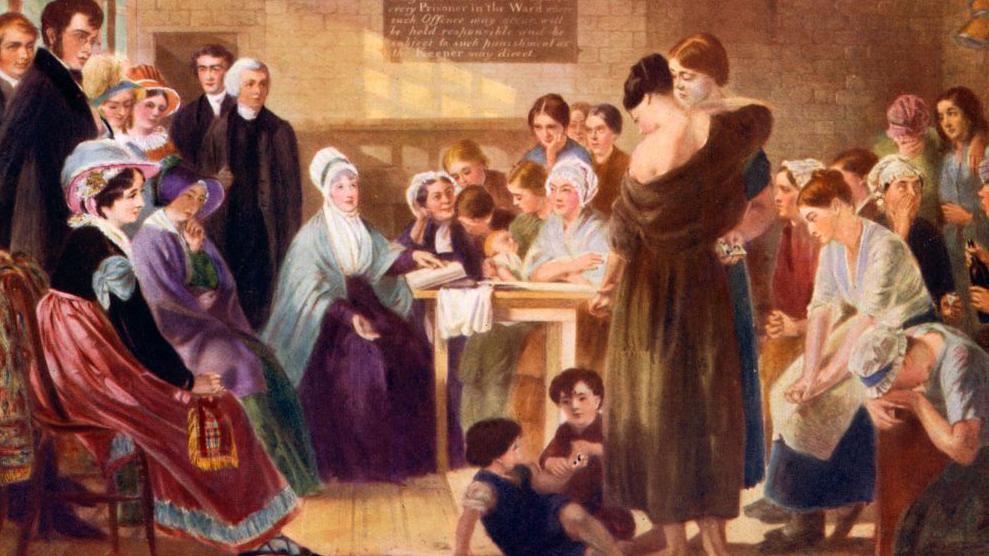 A vividly coloured drawing showing Elizabeth Fry sitting at a table in Newgate Prison in the early 19th Century. She has a book in front of her. To the right side are women prisoners, listening and talking, plus two small children playing. To her left are four well-dressed women and at least three clergymen in dark clothes. 