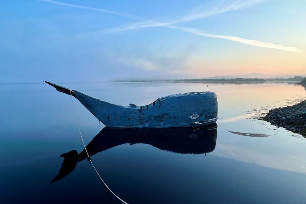 A whale-shaped boat and its reflection on the waters of Loch Linnhe