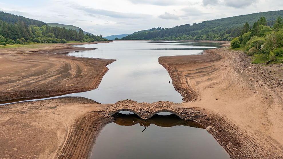 An exposed bridge and reservoir banks due to low water levels