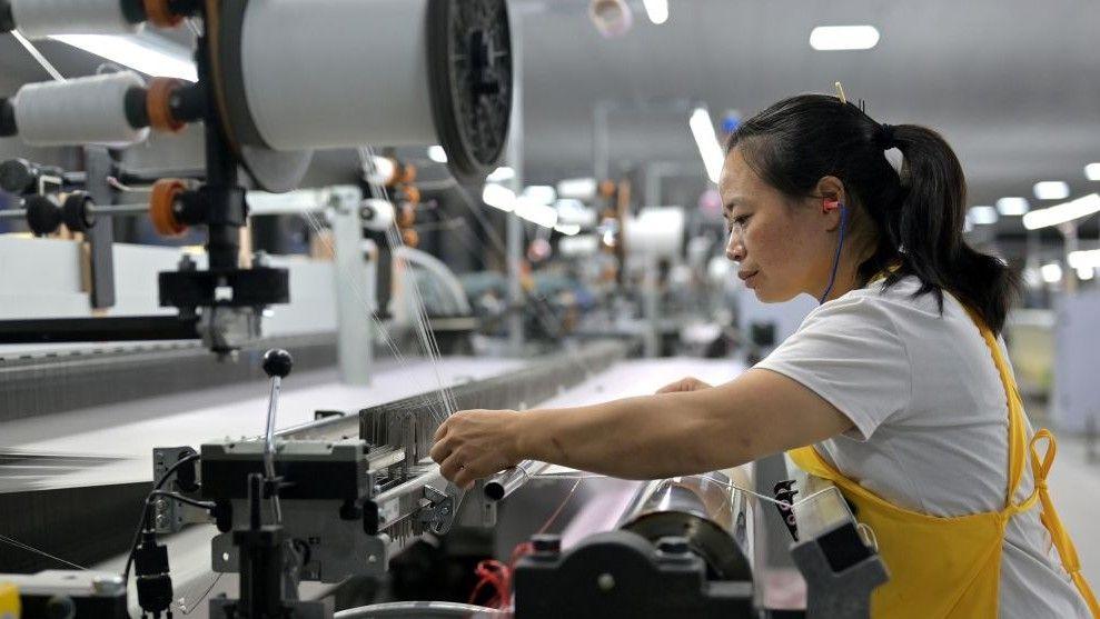 A lady works at a silk reeling machine in China.