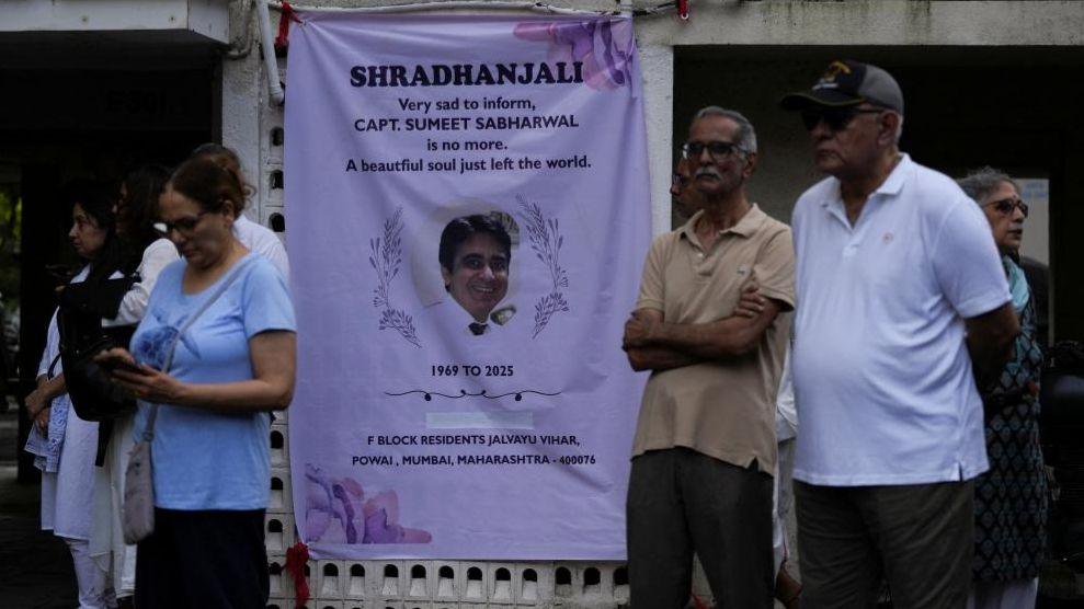 People stand next to a condolence banner as they wait for the body of Sumeet Sabharwal, a pilot who died when an Air India Boeing 787-8 Dreamliner crashed during take-off from an airport, to be handed over to his family in Mumbai, India, June 17, 2025.
