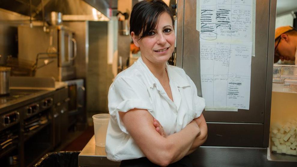 Amanda Cohen stands in her restaurant kitchen with her arms crossed