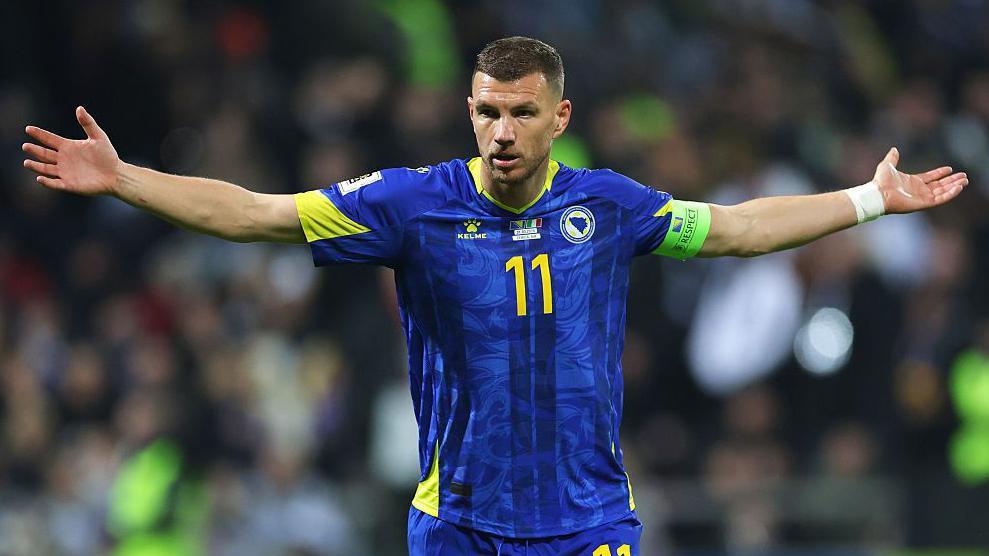Edin Dzeko with his arms out wide in a Bosnia-Herzegovina kit