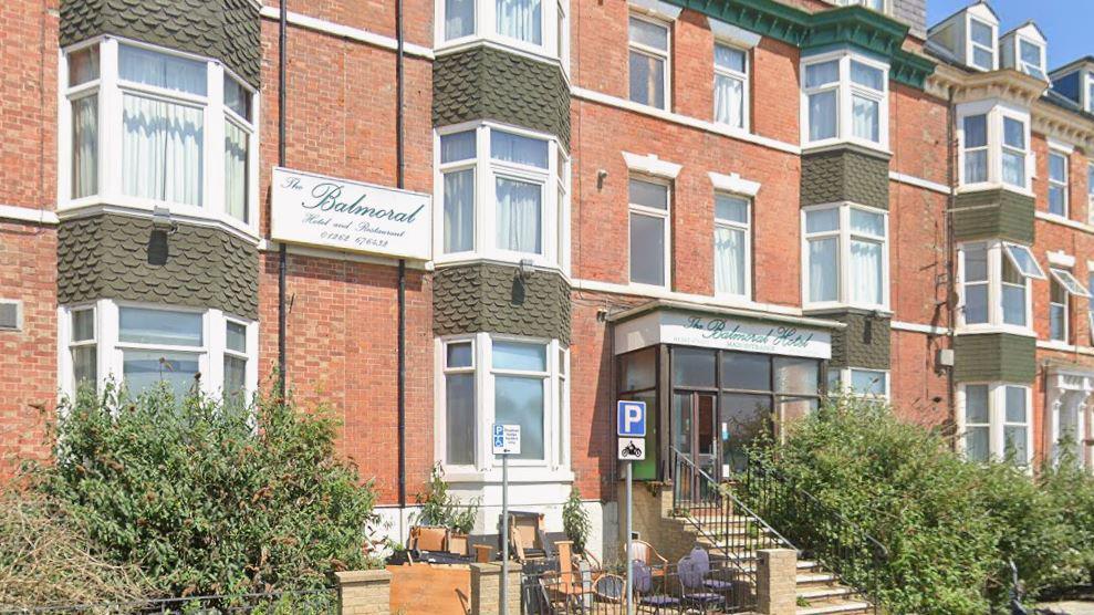 The outside of the former Balmoral Hotel in Bridlington. It is a large terraced red brick building white two white signs, one on the wall and one above the doorway. They read: "The Balmoral Hotel and Restaurant" in green writing.