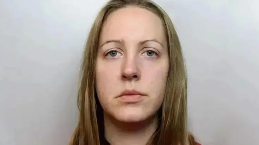 A custody photograph of Lucy Letby who has long blonde hair and and is wearing a red top.