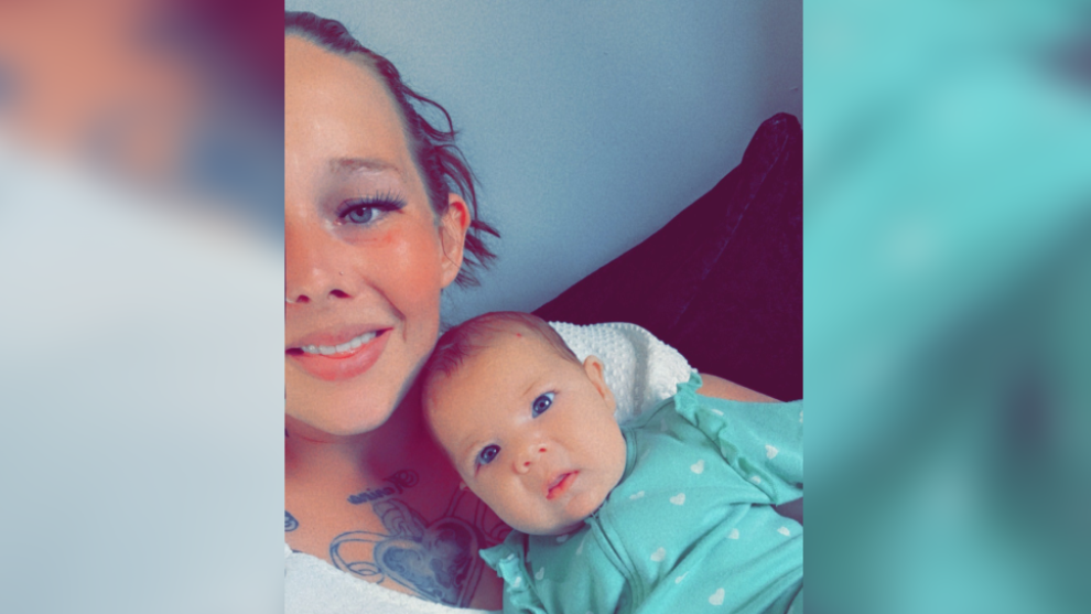 Mrs Black cradling her baby daughter Carmen, who is wearing a green babygro with white spots on it. The baby has blue eyes and is looking at the camera