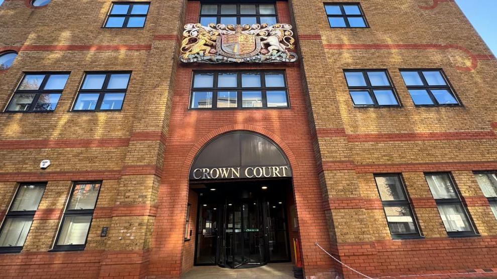 St Albans Crown Court, view of the brown and orange brick building from the outside, with ''Crown Court'' written above the rotating black doors. 
