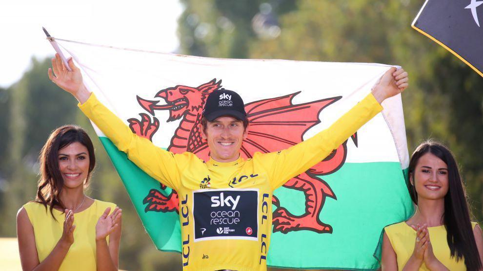 Geraint Thomas yn dal baner Cymru ar ôl ennill y Tour de France yn 2018.