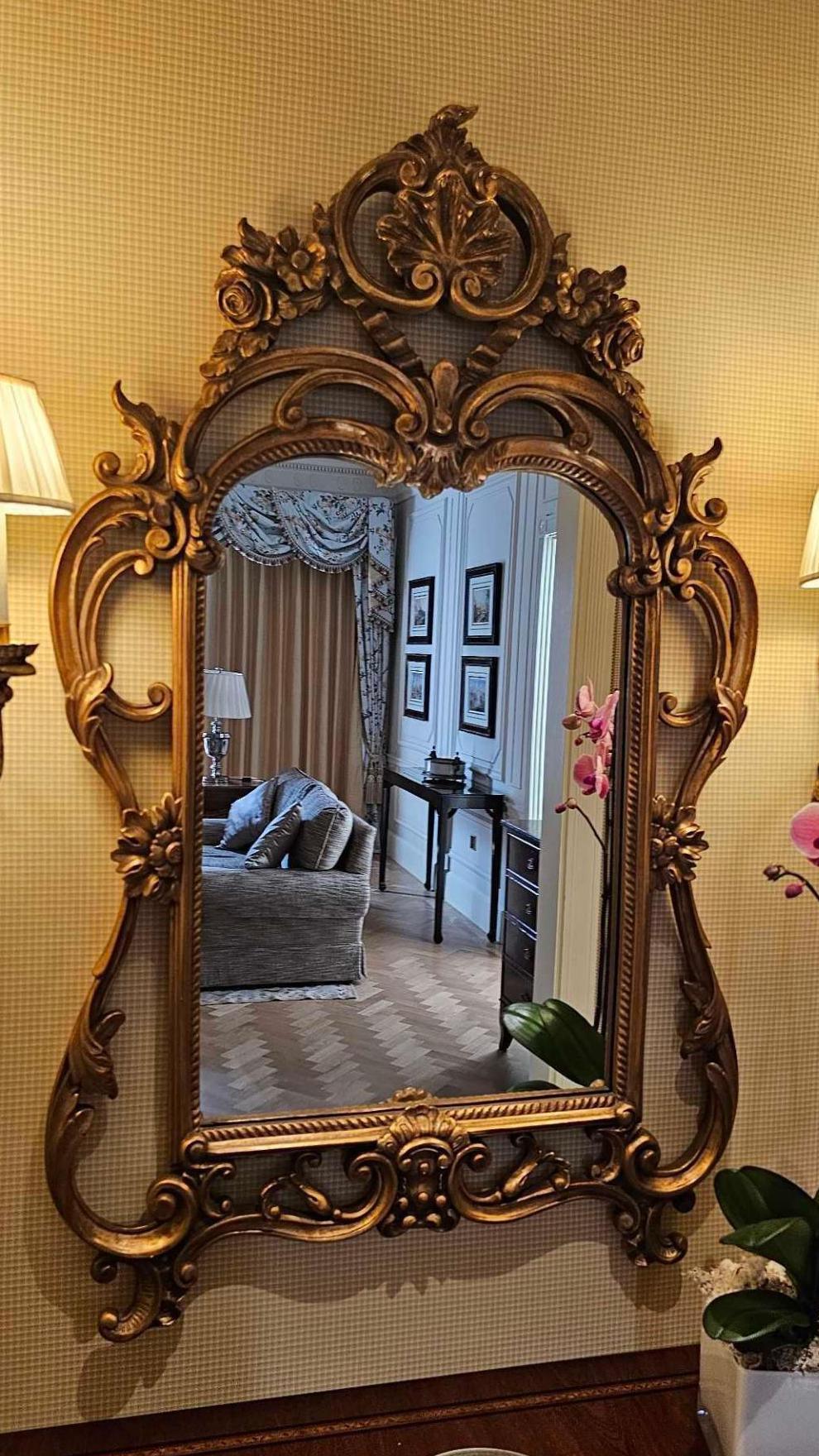 A Rococo style cartouche giltwood wall mirror. The mirror has an elaborate pierced rocaille cresting of shells and trailing flowers. 

