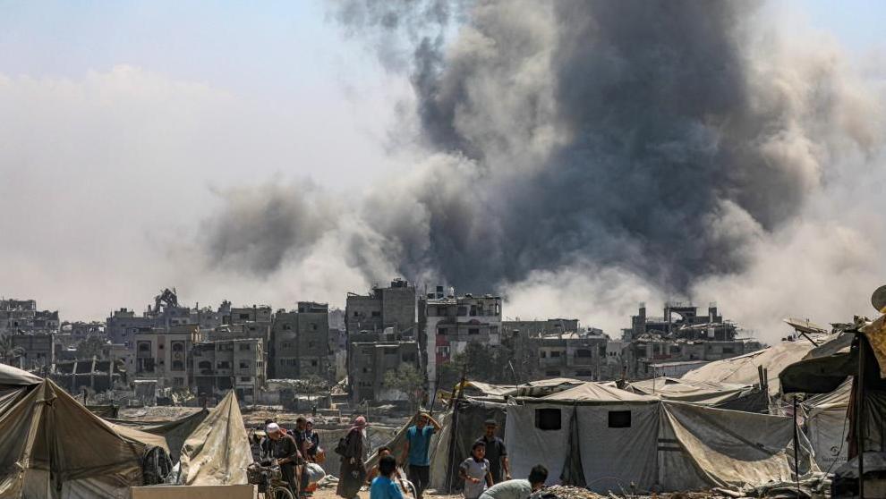 Palestinians flee as smoke is seen billowing over Gaza City following an Israeli air strike. Photo: 30 August 2025