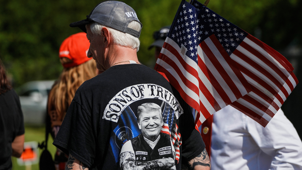 A man stands with his back to the camera holding an American flag while wearing a Trump T-shirt at a rally in Pittston on 16 July.