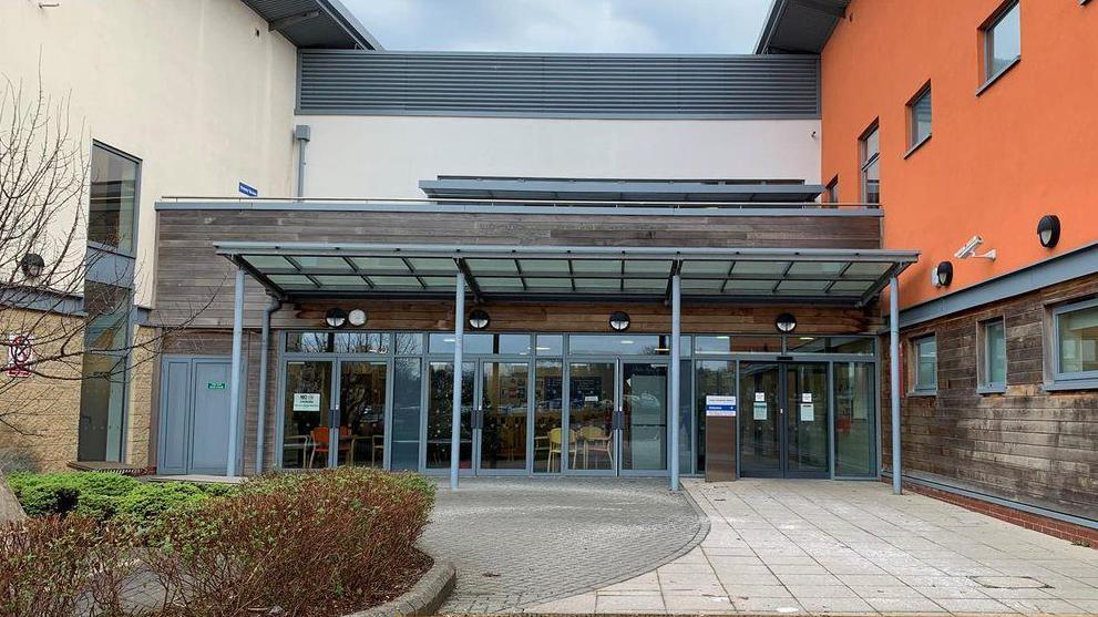 The entrance doors at Frome community hospital, which has orange and wooden-cladding on its outside walls.
