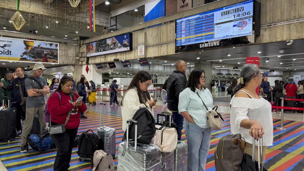 Passengers look at their phones as they queue at Simon Bolivar International Airport near Caracas.