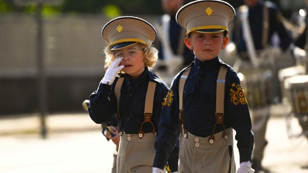 Two little boys in flute band uniforms wearing beige hats.