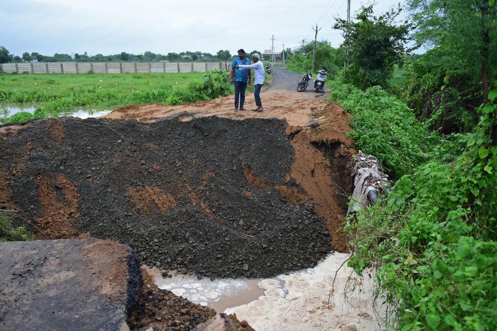 Onlookers inspect a road damaged by heavy rains on the outskirts of Ahmedabad on August 28, 2024. Intense monsoon rains and floods have battered the western Indian state of Gujarat, killing at least 28 people over the last three days, government officials said