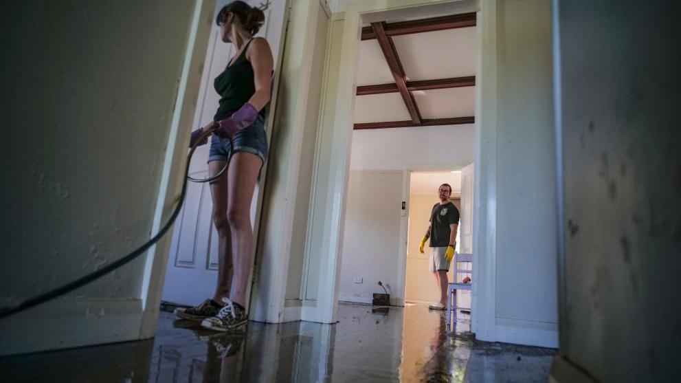 People clean a property following flooding in Taree, New South Wales