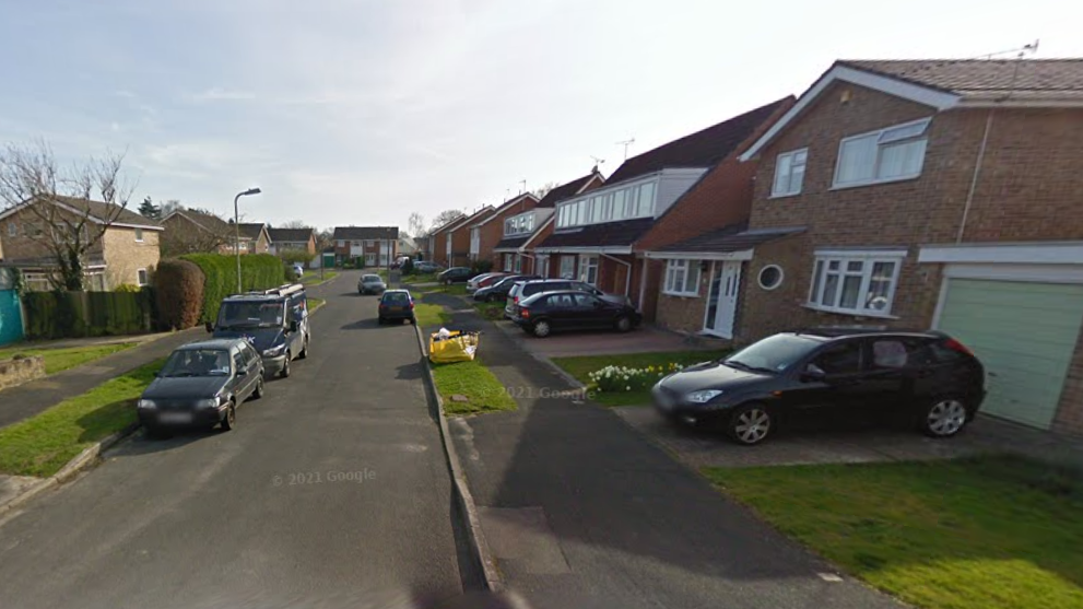 A residential street of semi-detached houses with cars parked in driveways
