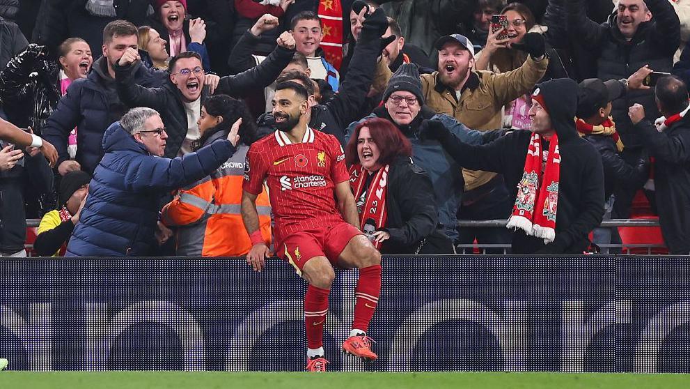 Mohamed Salah sits on an advertising hoarding in celebration