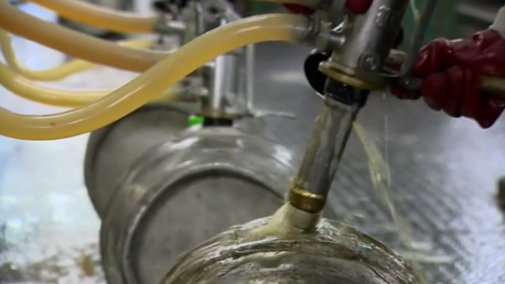 Barrels of beer are pictured having apparatus removed inside the brewery as beer pours out