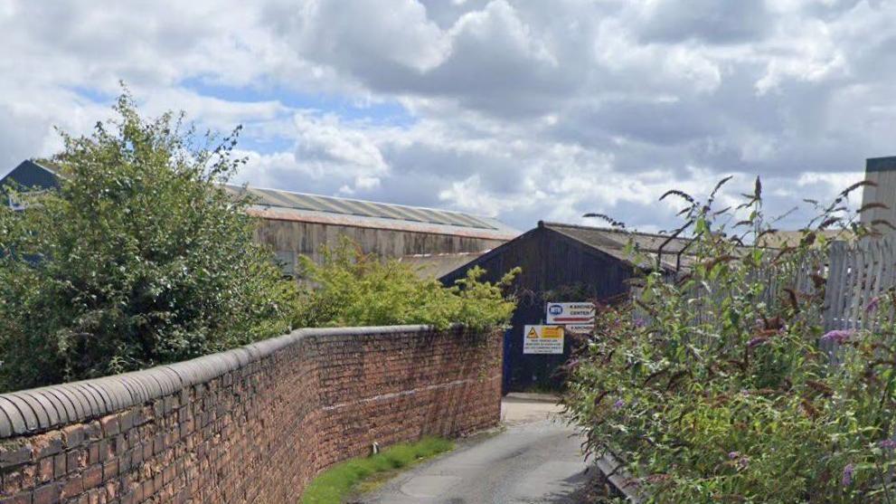 Google maps street view of Minerva lane. It is a small lane between a red brick wall and a metal gate