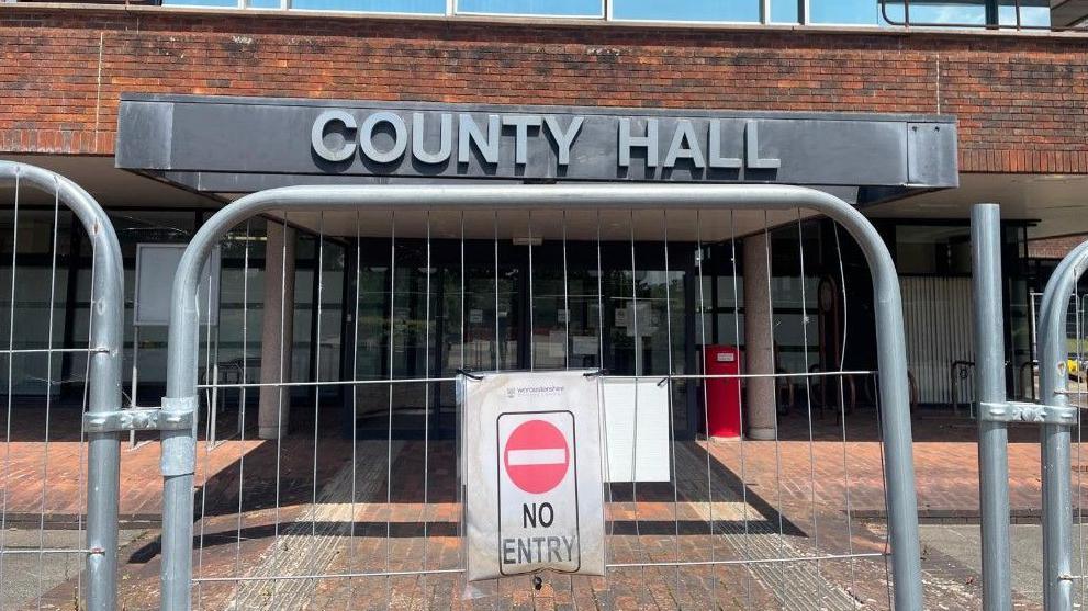 County Hall in Worcester, with a set of wire fences in front of it with a no entry sign