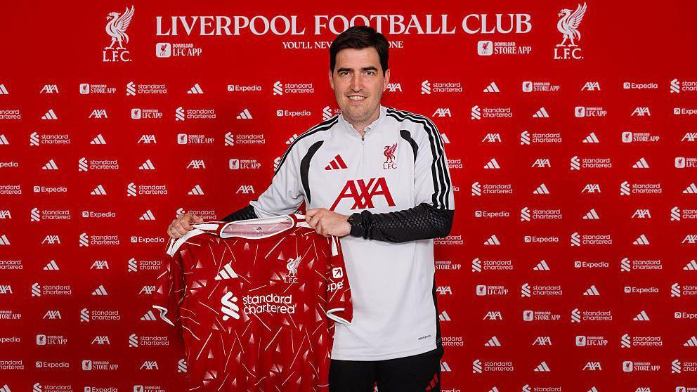 Andoni Iraola holding a Liverpool shirt.