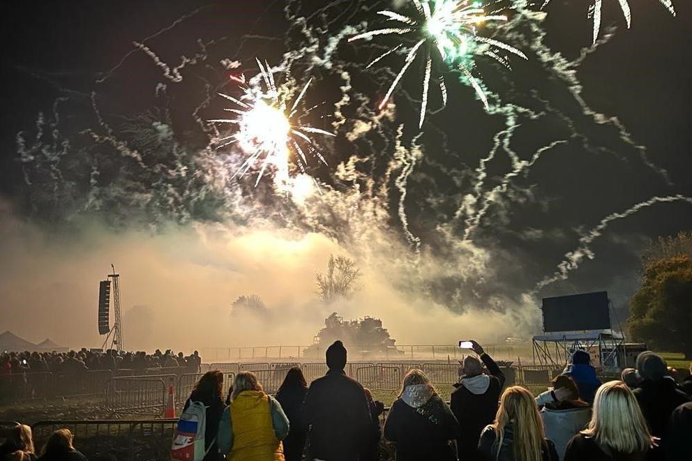 Onlookers look up to a fireworks display in South Park, as smoke flows atmospherically through the site.