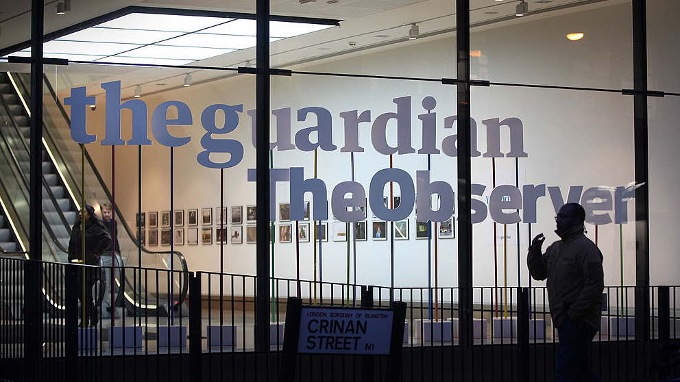 Man walks past The Guardian and The Observer's office in King's Cross, London 