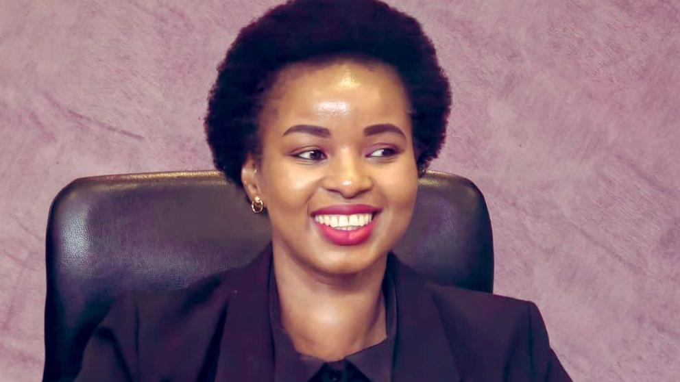 An image of Senamile Masango wearing an all black suit and smiling.