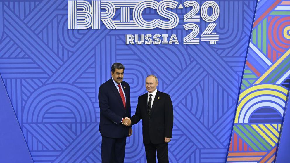 Venezuela's President Nicolás Maduro shakes hands with his Russian counterpart, Vladimir Putin, in front of a sign promoting the 2024 Brics summit in Kazan