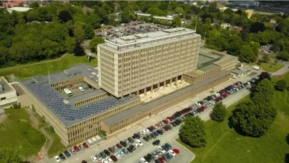 An aerial view of County Hall in Norwich, a central tower block surrounded by smaller two and three-storey buildings and a car park.