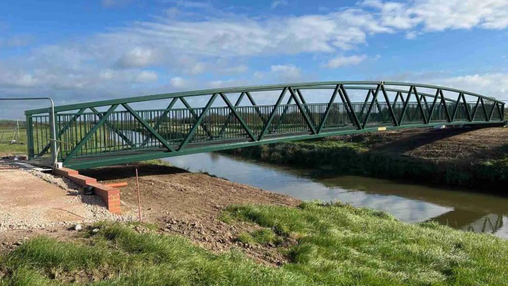 A green metal bridge over a river. 