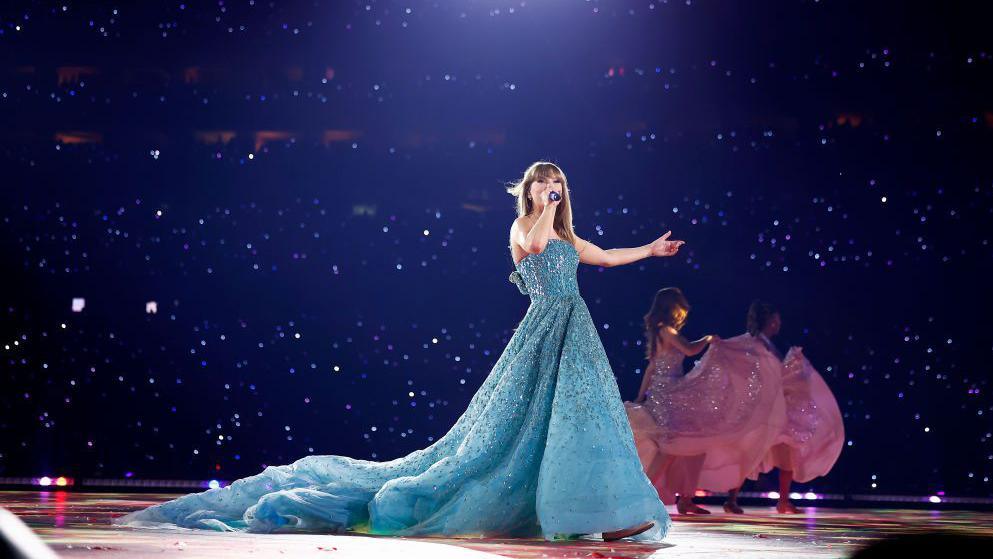Taylor in blue dress performing on the Eras Tour 