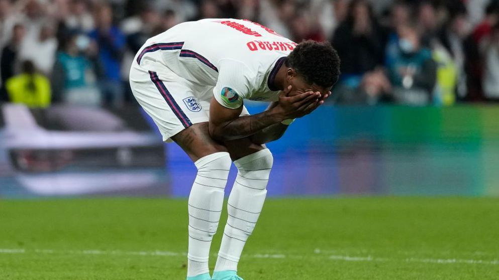 Marcus Rashford holds his head in his hands after missing a penalty. 