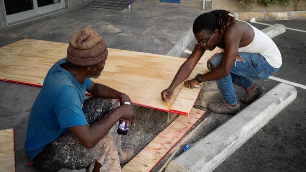 Workers board up a store window in a shopping plaza as Hurricane Beryl approaches, in Kingston, Jamaica, July 2, 2024