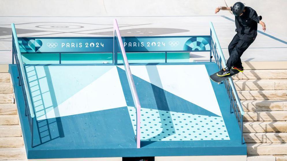 Liz Akama of Team Japan performs a trick on a railing on the street skateboarding course