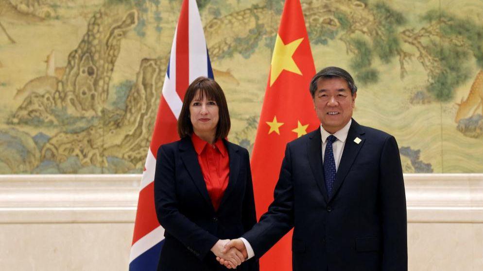 Chinese Vice-Premier He Lifeng and Britain's Chancellor Rachel Reeves shake hands before flags of China and the UK at a summit in Beijing