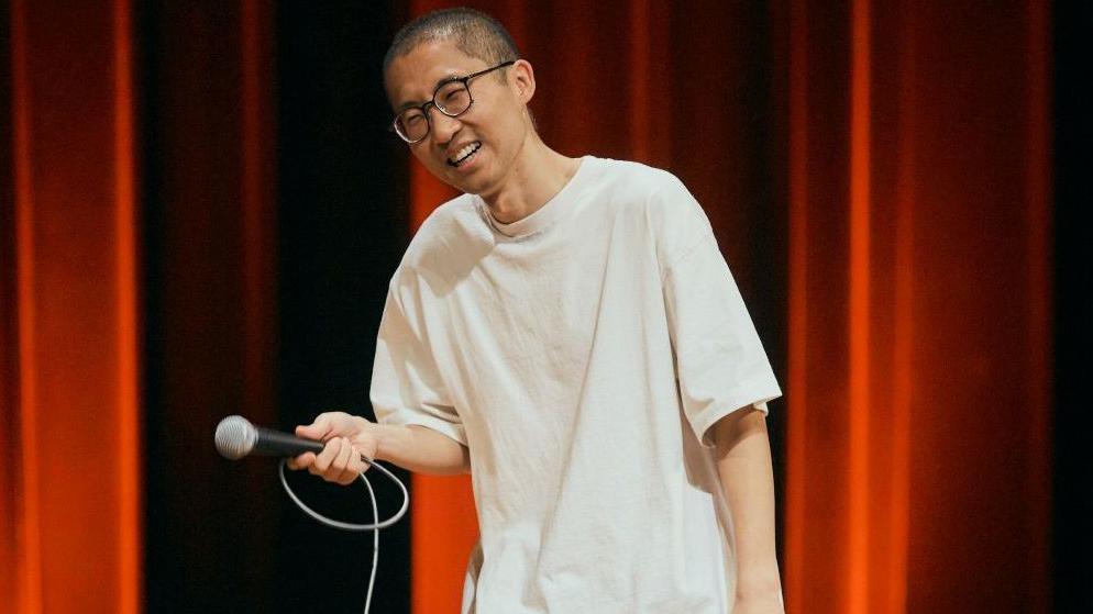 Chizi performs on stage in Taipei in April 2026, wearing a white oversized T shirt and a pair of glasses.