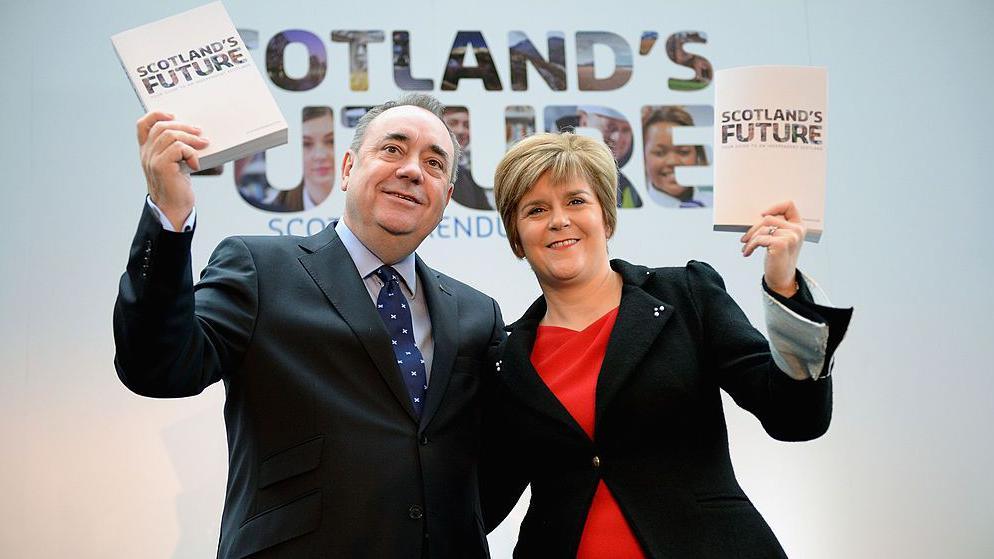 Alex Salmond and Nicola Sturgeon holding copies of the White Paper for Scottish independence at a launch event in Glasgow in 2013. The publication, and the background, feature the words Scotland's Future.