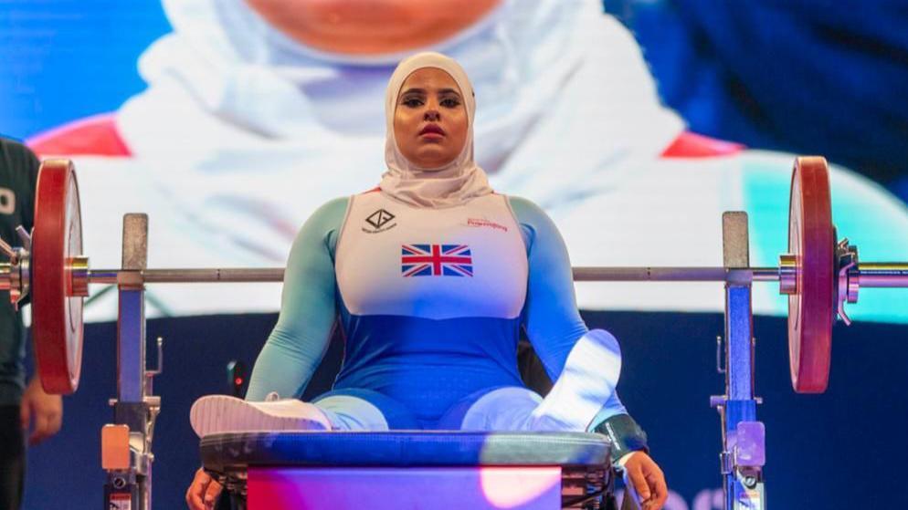 Doaa Shayea pictured on a weights bench in her Team GB outfit which is white with light blue sleeves. 