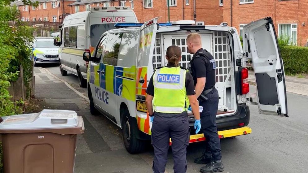 A suspect is locked inside the back of a small police van