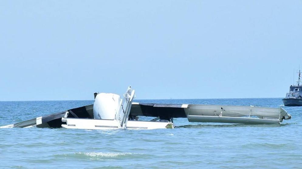 Wreckage of the plane lies partly submerged in shallow water in the sea off the coast of Thailand.