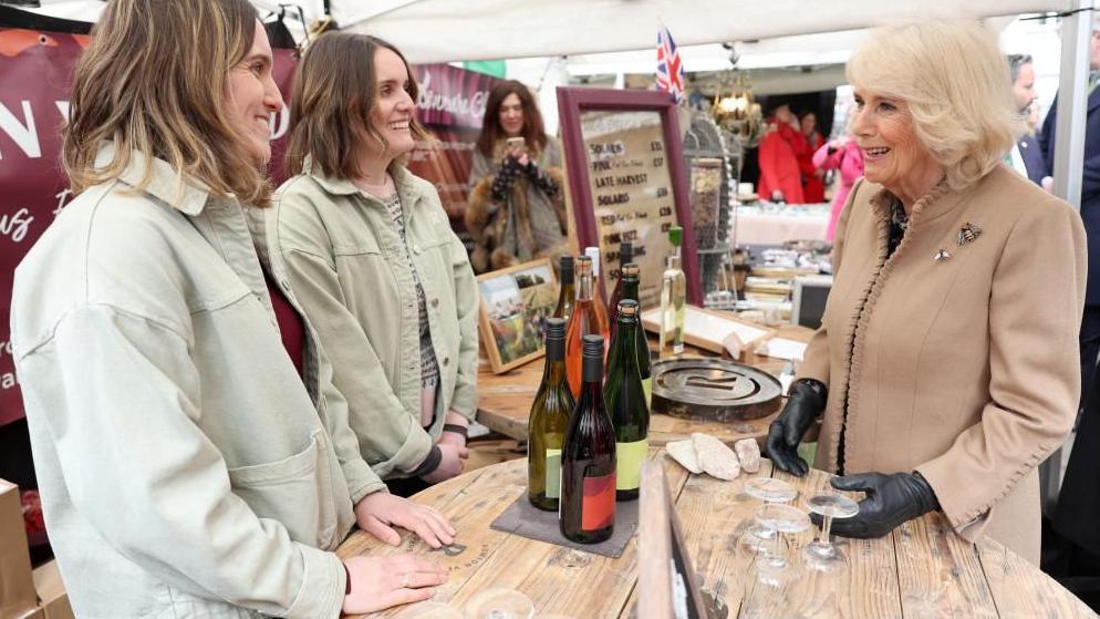 Two stallholders smiling as they talk to the Queen