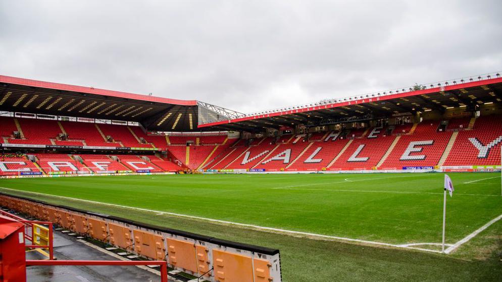 Charlton play at The Valley, seen here with empty stands featuring red seats with large white letters spelling out CAFC at one end and The Valley down one side.