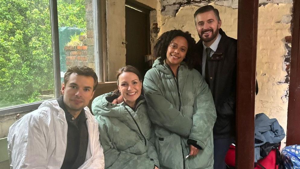 Catherine Ayers and other actors starring in 'Missing You' pose at one of the set locations. They are wearing body warmers.