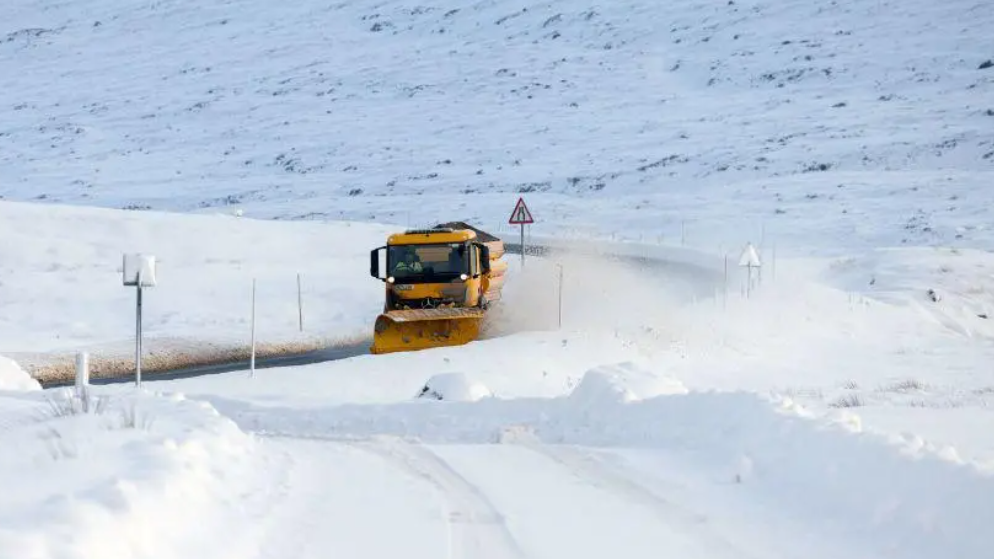 Làraidh a' glanadh an t-sneachda bho rathad air a' Ghàidhealtachd